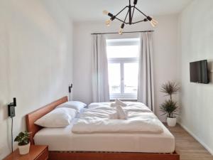 een slaapkamer met een bed met witte lakens en een raam bij Rosa Rooms Meran in Merano