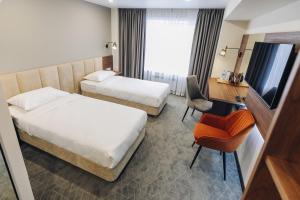 ウラン・ウデにあるホテル ブリアティアのベッド2台、デスク、テレビが備わるホテルルームです。