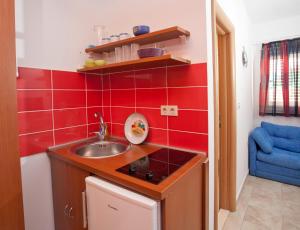 una pequeña cocina con fregadero y azulejos rojos en Apartments Fani, en Brela