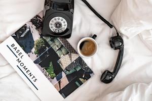 una macchina fotografica e una tazza di caffè su un letto di ART HOUSE Basel - Member of Design Hotels a Basilea
