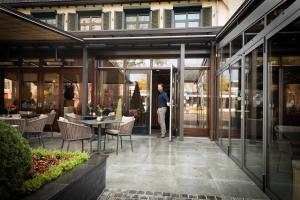 un homme debout à l'entrée d'un bâtiment dans l'établissement Hotel Café Restaurant De Ploeg, à Varsseveld