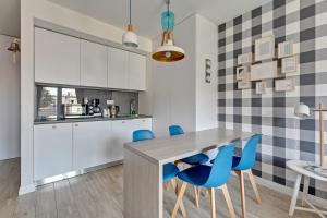 a kitchen with a table and blue chairs at Grand Apartments - Tartaczna Sailor Studio Gdańsk in Gdańsk