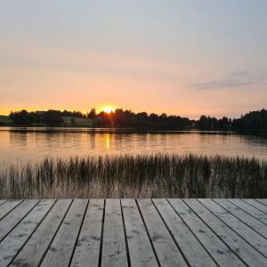 a wooden dock in front of a lake at sunset at Domek Nad Jeziorem in Sierakowice