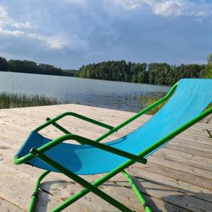 a blue chair sitting on a dock next to a lake at Zakątek Nad Jeziorem in Łyśniewo