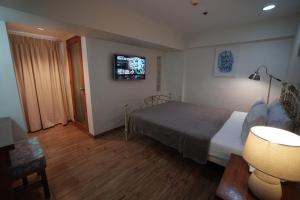 a bedroom with a bed and a tv on the wall at 1775 Adriatico Suites in Manila