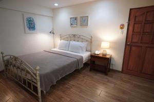 a bedroom with a bed and a table with a lamp at 1775 Adriatico Suites in Manila