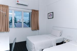 a hotel room with two beds and a window at Ridel Sunset Hotel in Kota Bharu