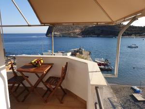 una mesa y sillas en un balcón con vistas al océano en The eagle en Kali Limenes