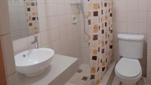 a bathroom with a sink and a toilet and a shower curtain at 1775 Adriatico Suites in Manila