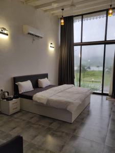 a bedroom with a large bed and a large window at Mountain N Lake Resort in Igatpuri