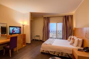 um quarto de hotel com uma cama, uma secretária e uma televisão em Porto El Jabal Hotel em Ain Sokhna