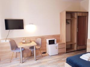 Gościniec Piast Hotel i Camping في Brzeźno: غرفة مع طاولة وكراسي وتلفزيون