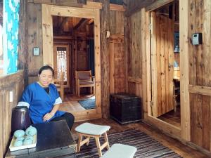 une femme assise dans une pièce avec cuisinière dans l'établissement Lost World Sanjiang Guest house, à Sanjiang