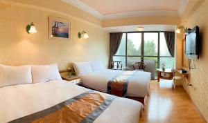 a hotel room with two beds and a television at Kao Feng Hotel in Zhongzheng