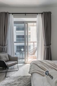 a bedroom with a bed and a chair and a window at HiGuests - Cloudy Apt, 10-min walk to Dubai Harbor in Dubai