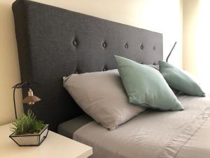 a bed with a gray headboard with pillows on it at Castelo do Relógio by Férias em Figueira in Figueira da Foz