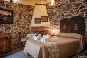 a bedroom with a bed and a stone wall at Domo Sa Barra in SantʼAntìoco