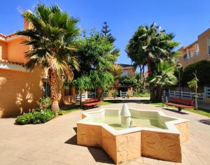 una fuente en medio de un patio con palmeras en Villa Laguna - your duplex in the sun!, en Vera
