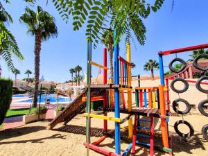 un colorido parque infantil en un complejo con piscina en Villa Laguna - your duplex in the sun!, en Vera