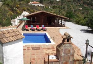 een zwembad met stoelen en een huis bij Casa de Madera in Sedella