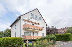 a white house with wooden balconies on a street at CASSEL LOFTS - Komfortable Wohnung für 4 - nahe SMA & Fulda in Niestetal