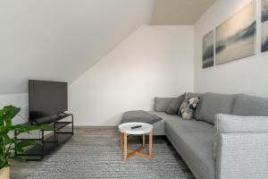 a living room with a gray couch and a table at CASSEL LOFTS - Komfortable Wohnung für 4 - nahe SMA & Fulda in Niestetal