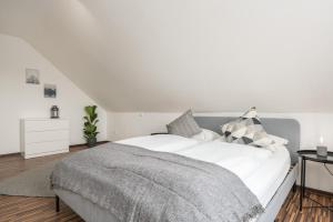 a bedroom with a white bed with a gray blanket at CASSEL LOFTS - Komfortable Wohnung für 4 - nahe SMA & Fulda in Niestetal