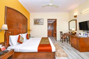 Habitación de hotel con cama grande y escritorio. en The Beaufort Inn en Nueva Delhi