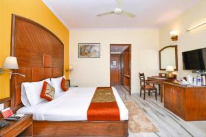 a hotel room with a large bed and a desk at The Beaufort Inn in New Delhi