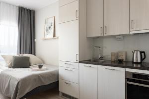 a white kitchen with a bed and a sink at Noli Myyrmäki in Vantaa