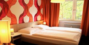 a bedroom with a bed and a window with red curtains at Hotel Madeleine Biohotel in Saarbrücken
