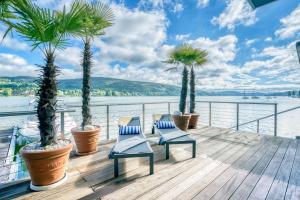 eine Terrasse mit Palmen, Stühlen und Wasser in der Unterkunft Hotel Parks in Velden am Wörthersee