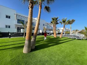 a woman walking through a park with palm trees at Island Home Fuerteventura in Corralejo