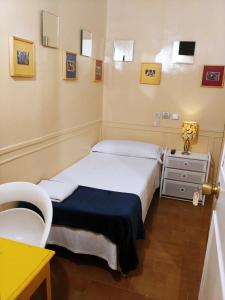 Habitación pequeña con 2 camas y mesa. en Hostal La Fontana, en Madrid