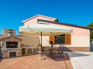 a table with an umbrella in front of a house at Holiday Home Medica - PZN318 by Interhome in Tinjan