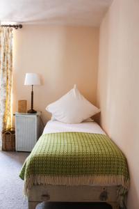 a bed with a green blanket and a white pillow at The Bull Inn in Totnes