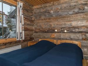 a bedroom with a wooden wall with a bed and a window at Holiday Home Ahmanportti 2 by Interhome in Ylläs