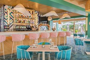un restaurante con sillas rosas y azules y un bar en Barceló La Nucía Palms, en La Nucía
