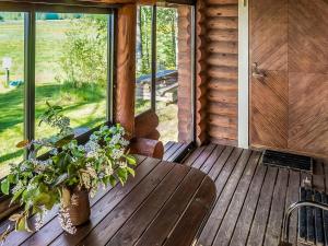 un porche de una cabaña de madera con mesa y plantas en Holiday Home Huvilakoti 2 by Interhome en Puromäki