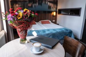 a room with a table with a vase of flowers and a laptop at Apart Neptun in Gdańsk