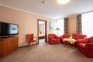 Aparthotel Hohenzollern في باد كيسينغن: غرفة معيشة بأثاث احمر وتلفزيون بشاشة مسطحة