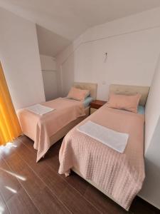 two beds in a small room with orange and white at Apartmani Selektor in Bijelo Polje