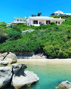 een huis bovenop een heuvel naast een strand bij Bosky Dell on Boulders Beach in Simonʼs Town