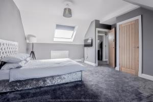 een witte slaapkamer met een bed en een dakraam bij Beautiful modern open plan living with Hot Tub in Kelty