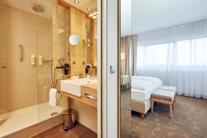 
a hotel room with a bath tub, toilet and sink at H+ Hotel Salzburg in Salzburg
