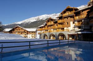 a resort with a swimming pool in the snow at Résidence Les Alpages 4 étoiles - Appartement 4 personnes - Piscine, Hammam, Sauna, Jacuzzi - ValCenis 73480 in Lanslebourg-Mont-Cenis