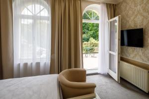 Pokój hotelowy z łóżkiem, krzesłem i oknem w obiekcie Villa Basileia Riverside w Karlowych Warach