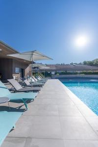 - une piscine avec des chaises longues et des parasols dans l'établissement Kyriad Résidence Cabriès - Plan de Campagne, à Cabriès