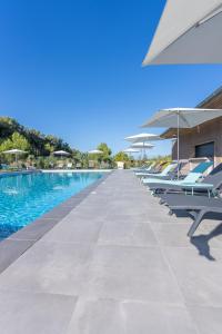 - une rangée de chaises longues et de parasols à côté de la piscine dans l'établissement Kyriad Résidence Cabriès - Plan de Campagne, à Cabriès