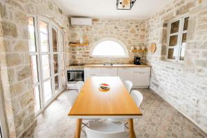 a kitchen with a wooden table and white chairs at Vila Leon - Old Qeparo in Qeparo